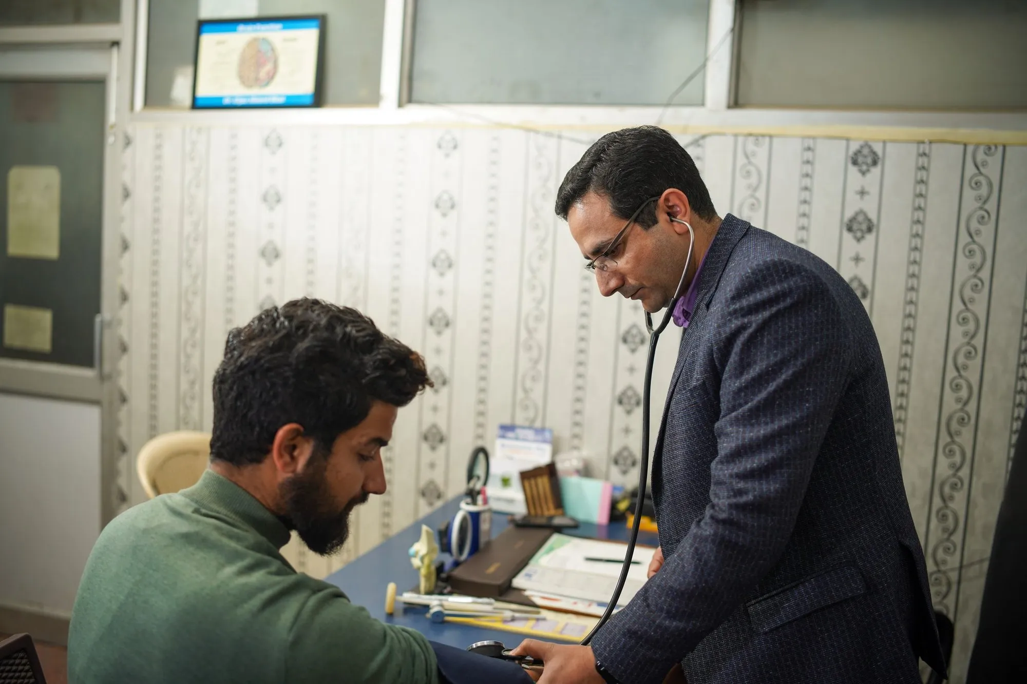Doctor checking a patient with a stethoscope and blood pressure cuff in a consultation room
